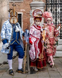 People in costume at the Venice Carnival in front of the Venetian Arsenal.