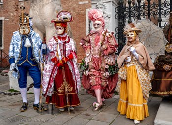 People in costume at the Venice Carnival in front of the Venetian Arsenal.