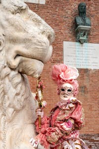 People in costume at the Venice Carnival in front of the Venetian Arsenal.