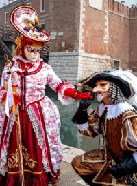 People in costume at the Venice Carnival in front of the Venetian Arsenal.