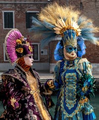 People in costume at the Venice Carnival in front of the Venetian Arsenal.