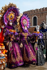 People in costume at the Venice Carnival in front of the Venetian Arsenal.