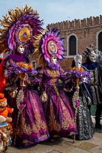 People in costume at the Venice Carnival in front of the Venetian Arsenal.